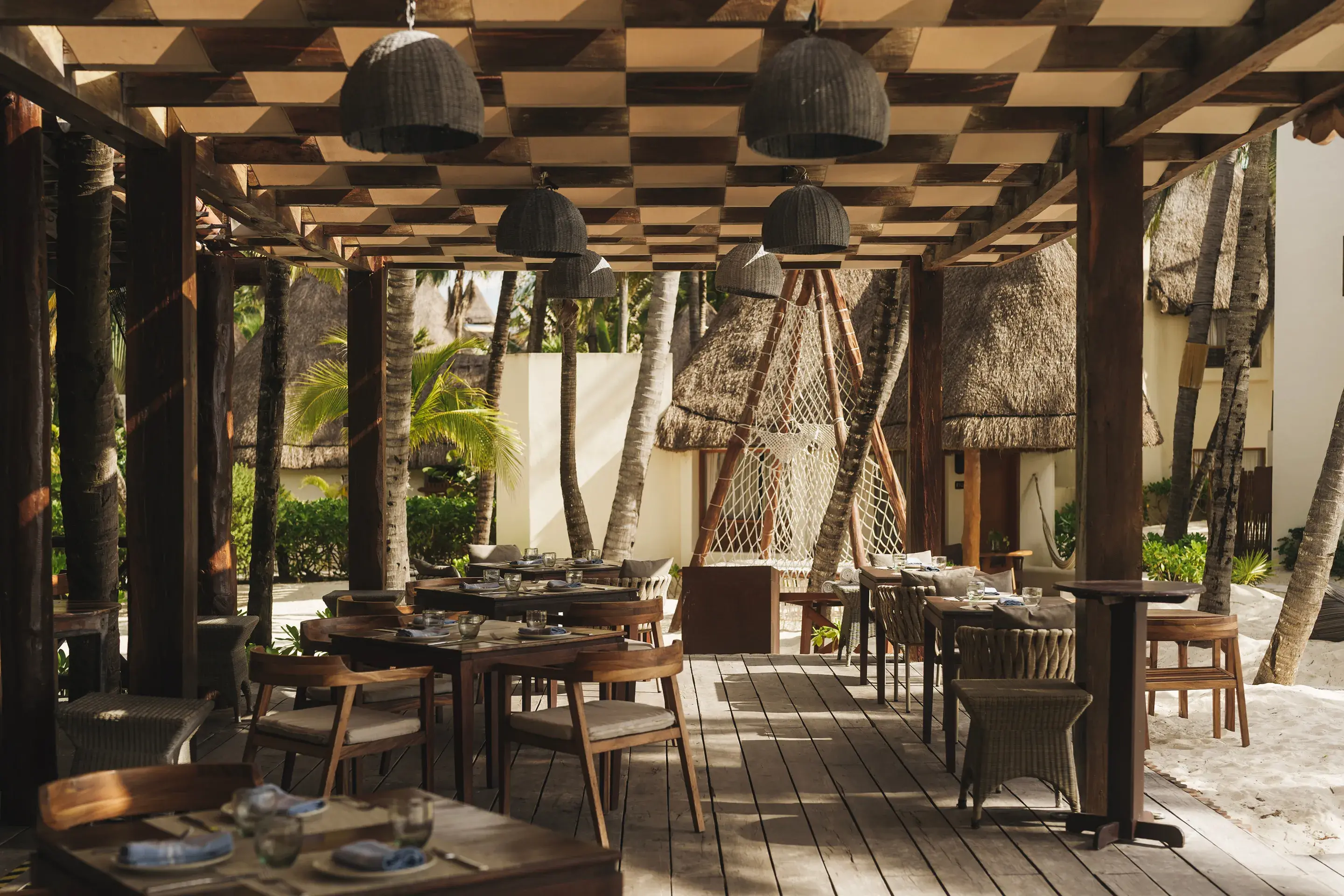 Beachfront restaurant terrace with tables under a palapa pergola