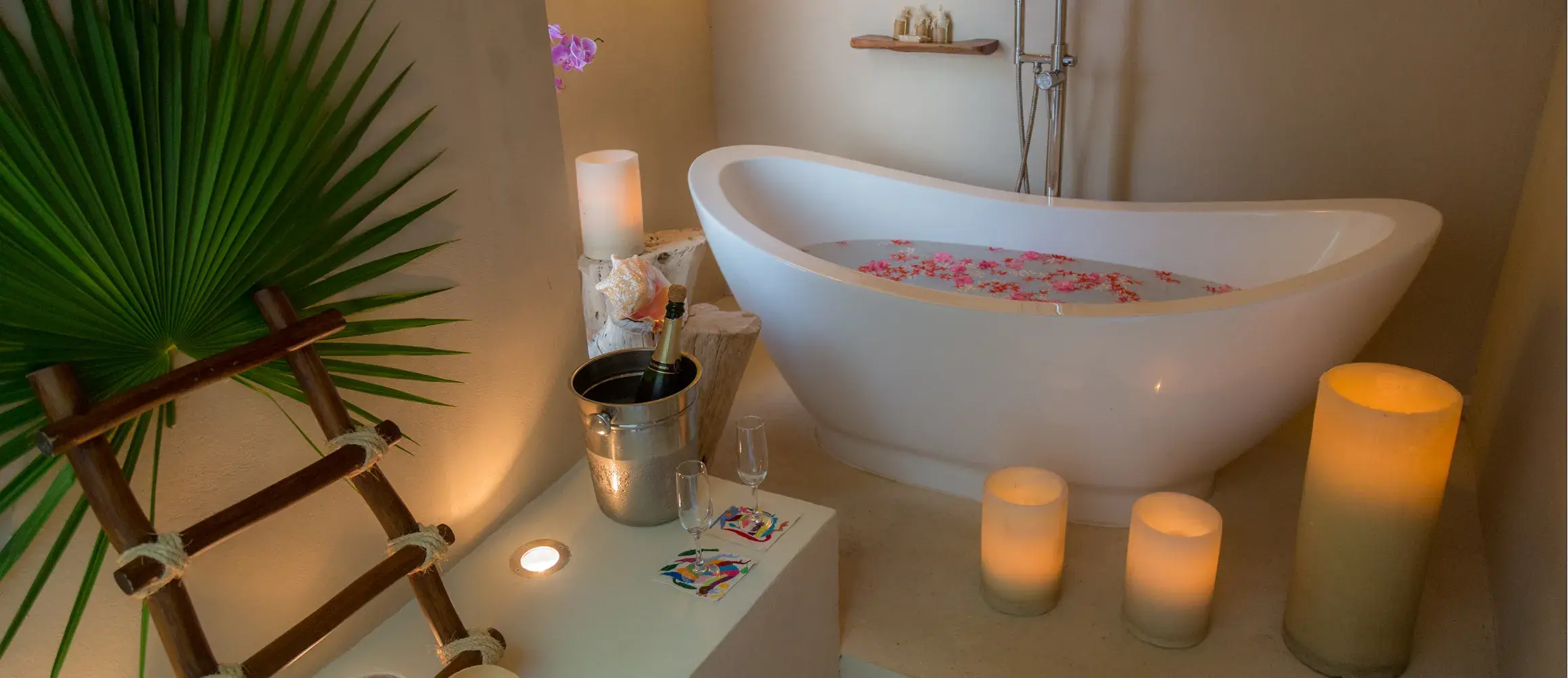 Bathtub with flower petals, candles and champagne for a spa ritual