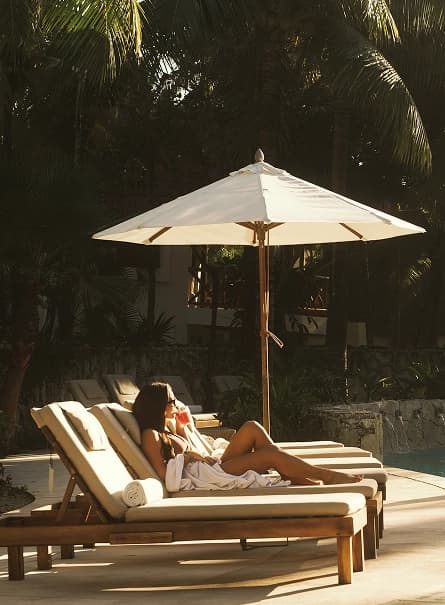 Huésped relajándose en un camastro junto a la alberca en Mahekal Beach Resort