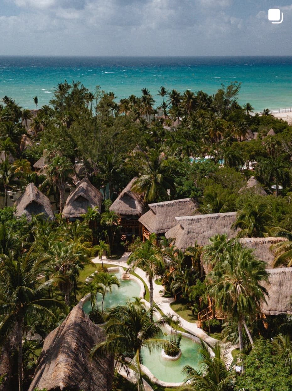 Vista aérea de Mahekal Beach Resort con sus albercas y palapas frente al mar
